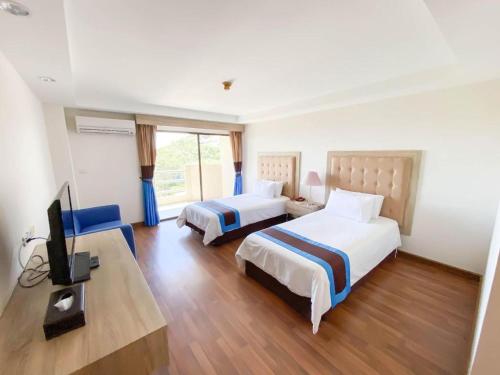 a hotel room with two beds and a flat screen tv at Blue Wave Hotel Hua Hin in Hua Hin