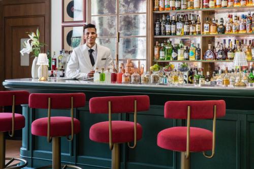 a man standing behind a bar with red bar stools at DLF Club 3 in Gurgaon