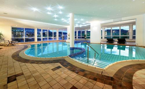 a large swimming pool in a building with windows at Hotel Alpenflora in Castelrotto