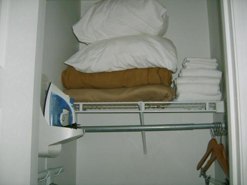 a pile of pillows and towels on a shelf in a room at Sunstyle Suites in Orlando