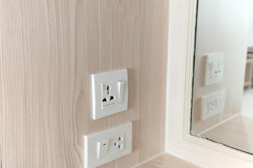a wall with two light switches and a mirror at Merlin Hotel in Sungai Kolok