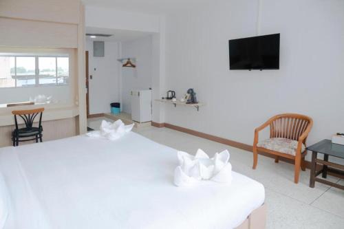 a room with two beds and a tv and a table at Merlin Hotel in Sungai Kolok