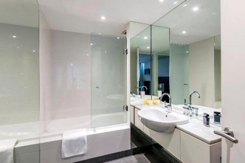 a white bathroom with a sink and a shower at Oaks Queenstown Club Suites in Queenstown