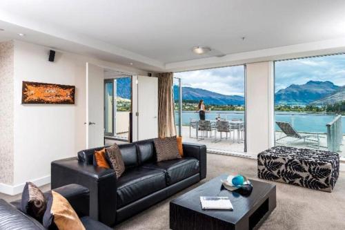 a living room with a black leather couch and a table at Oaks Queenstown Club Suites in Queenstown