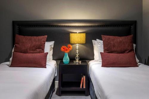 two beds with red pillows and a vase with flowers at Oaks Queenstown Club Suites in Queenstown