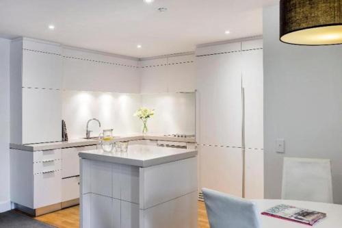 a white kitchen with a sink and a refrigerator at Oaks Queenstown Club Suites in Queenstown
