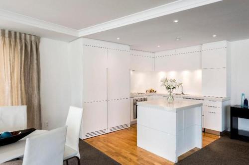 a kitchen with white cabinets and a table with flowers on it at Oaks Queenstown Club Suites in Queenstown