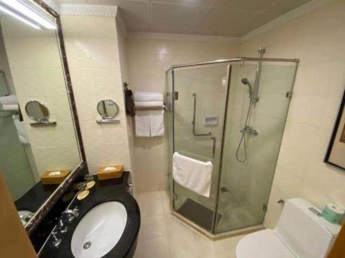 a bathroom with a shower and a toilet and a sink at Beijing Friendship Hotel Jing Bin Building in Beijing