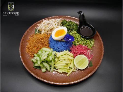 a plate of food with an egg and vegetables at Santisookmidtown Pattani in Kampong Rusamileh