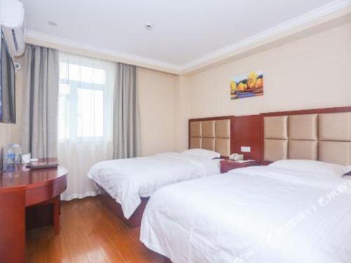 a hotel room with two beds and a desk at GreenTree Inn Suzhou Guanqian Street Leqiao Metro Station in Suzhou