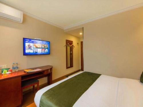 a bedroom with a bed and a desk and a tv at GreenTree Inn Suzhou Guanqian Street Leqiao Metro Station in Suzhou