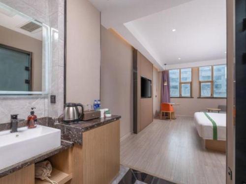a bathroom with a sink and a bed in a room at GreenTree Inn JiangSu Changzhou Lijia Town Wujin Road Business Hotel in Changzhou
