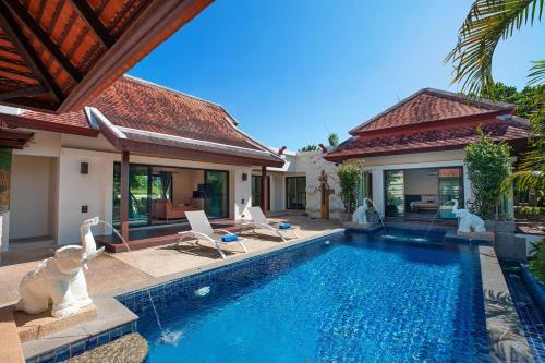 a villa with a swimming pool and a house at Tropical Living at 3BR Pool Villa Bianca, Baan Bua Luxury Estate, Nai Harn Beach in Rawai Beach