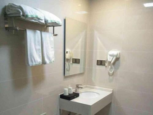 une salle de bain blanche avec un lavabo et un miroir dans l'établissement GreenTree Inn Yancheng Dongtai Fuan Town Express Hotel, à Anfeng