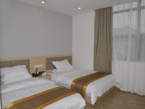 two beds in a hotel room with a window at Shell Shanghai Jiading Nanxiang Town Minzhu Street Hotel in Shanghai