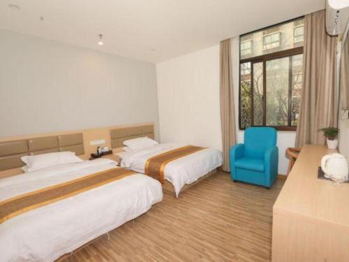 a hotel room with two beds and a blue chair at Shell Shanghai Jiading Nanxiang Town Minzhu Street Hotel in Shanghai