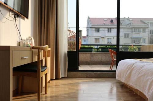 a bedroom with a bed and a desk and a window at Shell Shanghai Jiading Nanxiang Town Minzhu Street Hotel in Shanghai