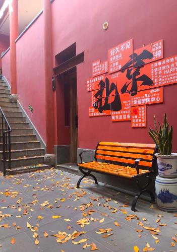 a bench sitting in front of a building with leaves on the ground at YOYO PINKE Hotel in Beijing
