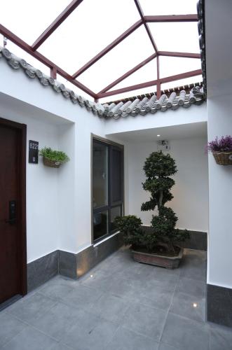 a building with a window and a bonsai tree in a courtyard at YOYO PINKE Hotel in Beijing