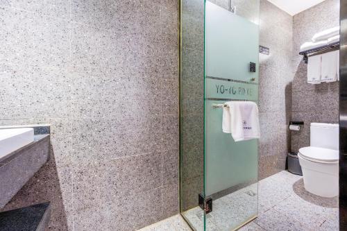 a bathroom with a toilet and a glass shower door at YOYO PINKE Hotel in Beijing