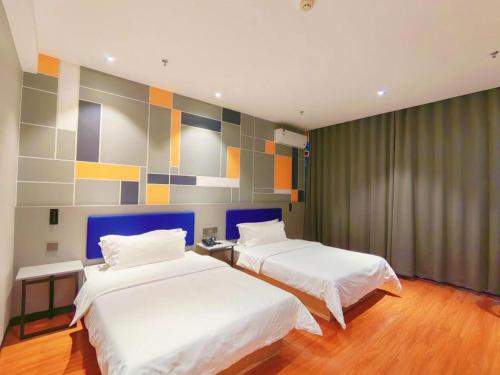 a bedroom with two beds and a colorful wall at 7 Days Inn Yining Xintiandi in Kipekyüzi