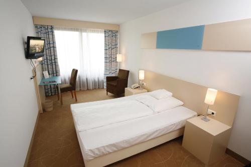 a hotel room with a white bed and a television at Hotel Schönbuch in Pliezhausen