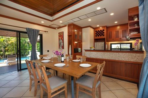 a kitchen and dining room with a wooden table and chairs at Tropical Living at 3BR Pool Villa Bianca, Baan Bua Luxury Estate, Nai Harn Beach in Rawai Beach