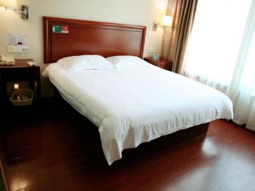 a bedroom with a large white bed with a wooden headboard at GreenTree Inn Rizhao Yantai Road in Rizhao