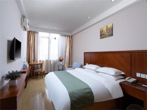 a hotel room with a large bed and a desk at GreenTree Inn Shanghai Caohejing Development Zone Songjiang Park Jiuxin Road Business Hotel in Chunshen