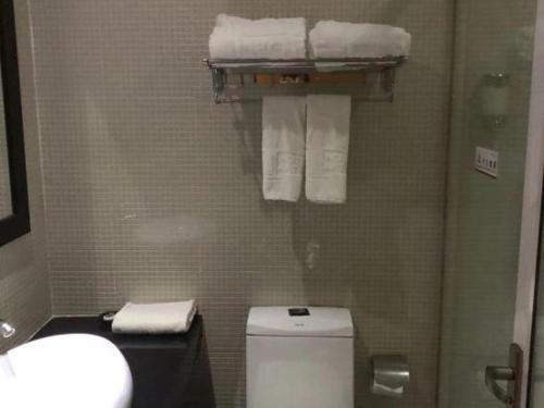 a bathroom with a toilet and a sink and towels at The Art Hotel in Shenzhen
