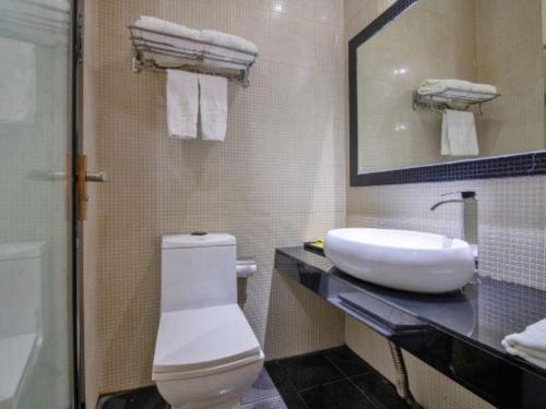 a bathroom with a sink and a toilet and a mirror at The Art Hotel in Shenzhen
