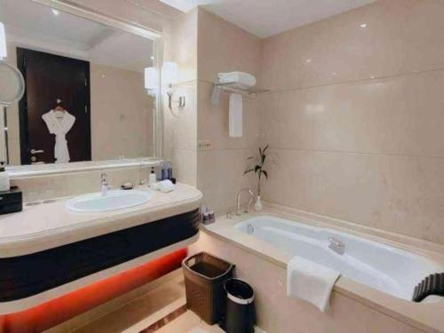 a bathroom with a sink and a tub and a mirror at Linyi Blue Horizon International Hotel Yi He in Linyi