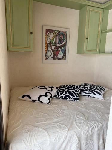 un lit avec deux oreillers et un tableau au mur dans l'établissement Beau studio provençal, à Mandelieu-la-Napoule