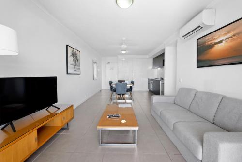 a living room with a couch and a flat screen tv at Pacific Sands Apartments Mackay in Mackay