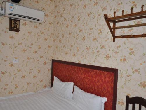 a bedroom with a bed with a red headboard and wallpaper at Pingyao Yufengheng Hotel in Pingyao