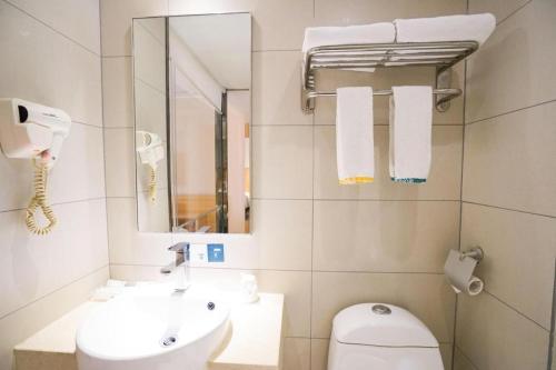 a bathroom with a sink and a toilet and a mirror at City Comfort Inn Wuhan High Speed Railway Station in Wuhan