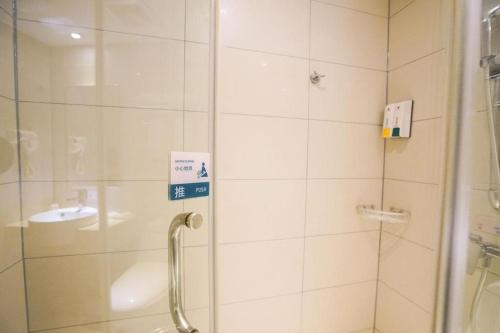 a shower with a glass door next to a sink at City Comfort Inn Wuhan High Speed Railway Station in Wuhan
