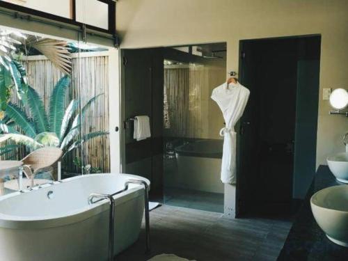 une salle de bain avec une baignoire et un peignoir sur un mannequin dans l'établissement Bravo Resorts - Munting Paraiso, à Dauin