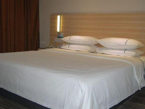 a large white bed with pillows on top of it at City Comfort Inn Foshan Shunde Daliang Qinghui Garden Xinsong in Shunde