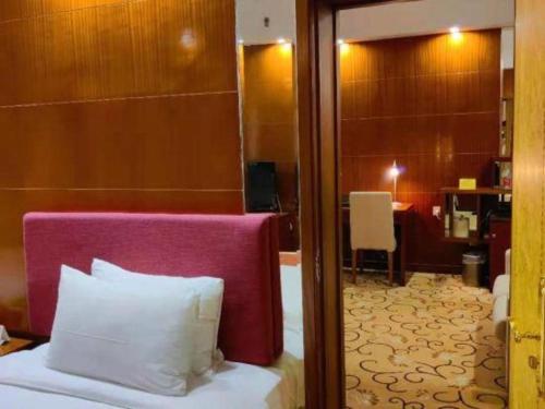 a bedroom with a bed with a purple headboard and a room at Golden Lustre Hotel in Shenzhen