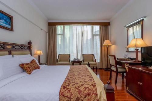 a bedroom with a large bed with a desk and a desk at Golden Lustre Hotel in Shenzhen