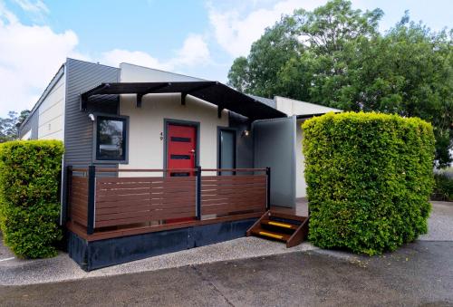 a small house with a red door and two bushes at Airport Tourist Village Melbourne in Melbourne