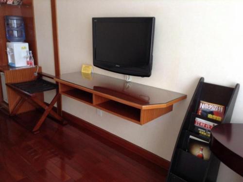 a flat screen tv on a wall with a desk at Golden Lustre Hotel in Shenzhen