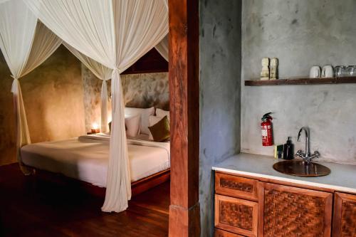 a bedroom with a canopy bed and a sink at ZIN Berawa Villas & Bungalows in Canggu