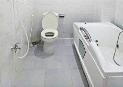 a white bathroom with a toilet and a bath tub at 95 Lam Son Hotel in Ho Chi Minh City