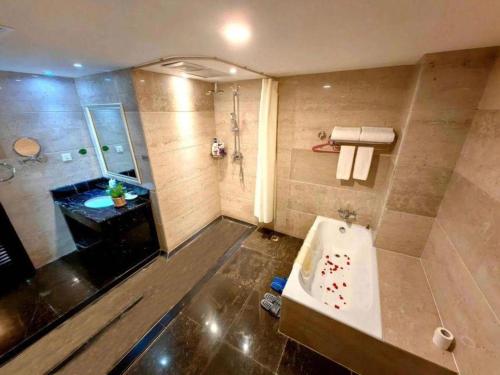 a bathroom with a tub and a shower and a sink at Shilin Yinruilin International Hotel in Lumeiyi