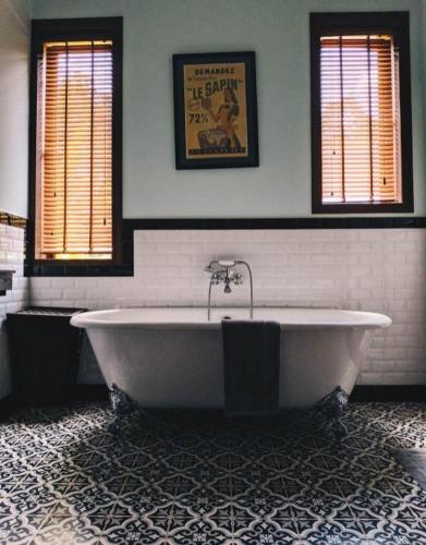 a large white tub in a bathroom with two windows at Le Relais de Chhlong in Kratie