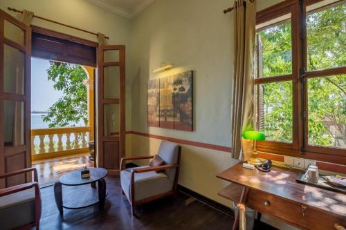 a living room with a table and some windows at Le Relais de Chhlong in Kratie