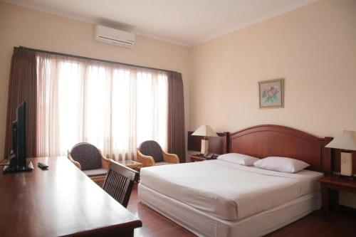 une chambre avec un lit, un bureau et une télévision dans l'établissement La Oma, à Bandung