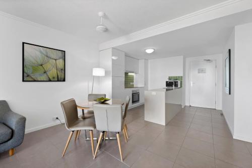 a dining room and kitchen with a table and chairs at Pacific Sands Apartments Mackay in Mackay